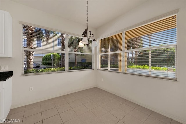 unfurnished dining area with light tile patterned floors and an inviting chandelier