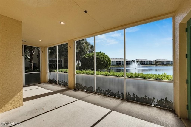 unfurnished sunroom featuring a water view