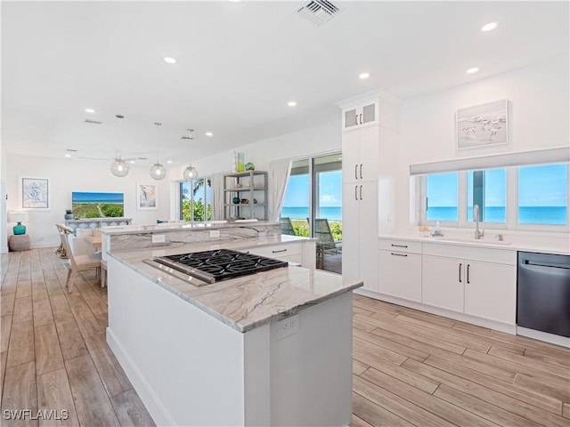 kitchen with white cabinets, appliances with stainless steel finishes, a center island, and hanging light fixtures