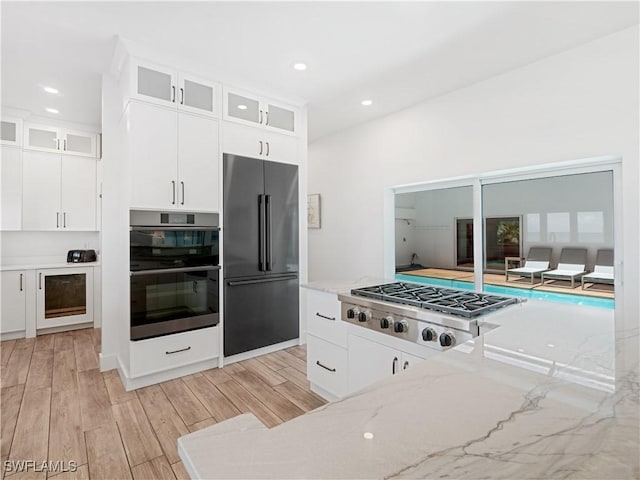 kitchen with light stone countertops, white cabinetry, and stainless steel appliances