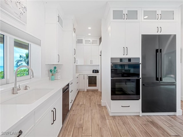 kitchen with white cabinets, light hardwood / wood-style floors, sink, and appliances with stainless steel finishes