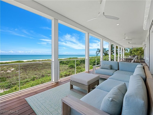 sunroom with a beach view, a water view, and ceiling fan