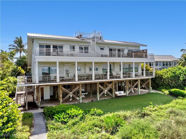 rear view of property featuring a yard and a balcony