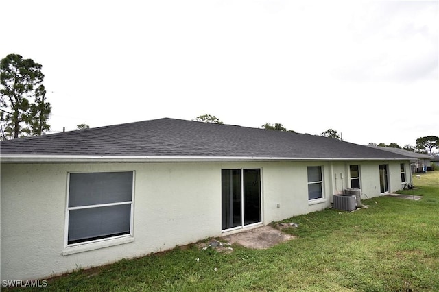 rear view of property featuring central AC unit and a yard