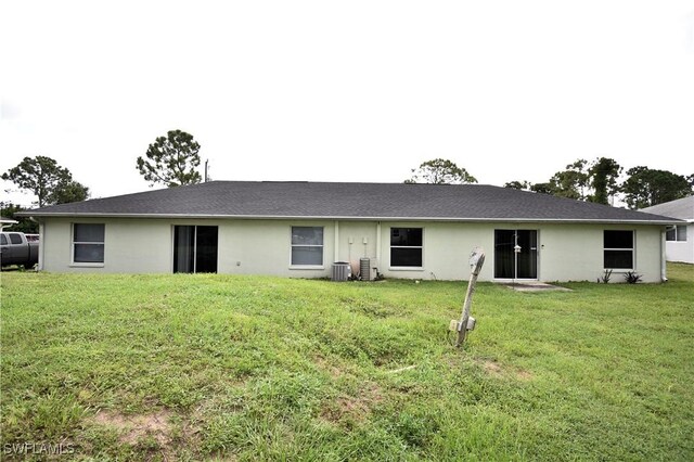 rear view of house featuring a lawn and central AC unit