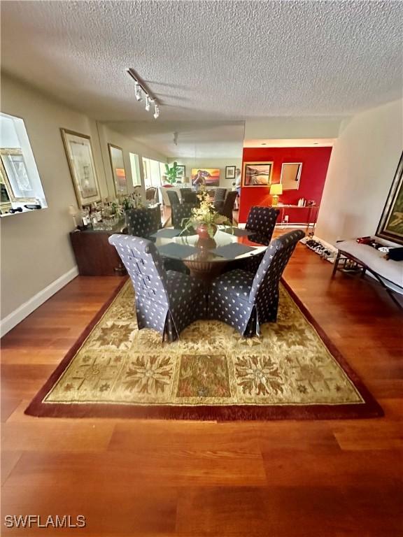 dining area with baseboards, a textured ceiling, and wood finished floors