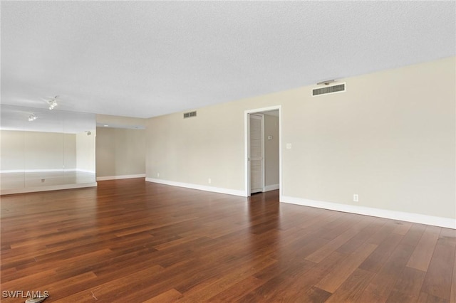 empty room with baseboards, wood finished floors, visible vents, and a textured ceiling