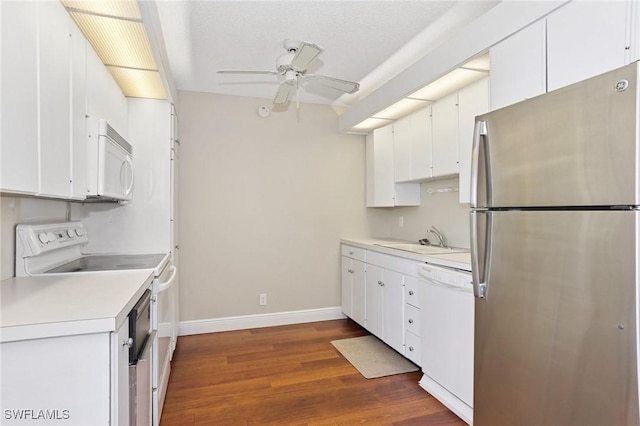 kitchen with a sink, white appliances, dark wood-type flooring, and light countertops