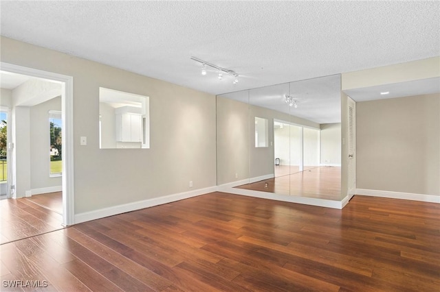 unfurnished room with baseboards, a textured ceiling, and wood finished floors