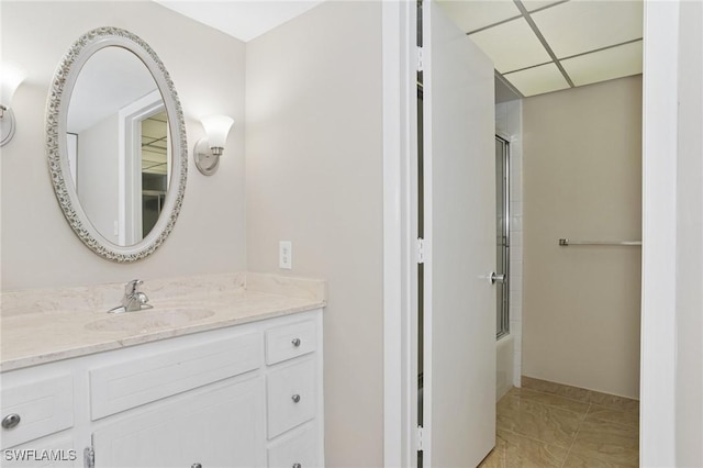 bathroom featuring a drop ceiling, vanity, and shower / bath combination with glass door