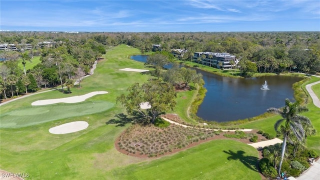 drone / aerial view featuring a water view, view of golf course, and a wooded view