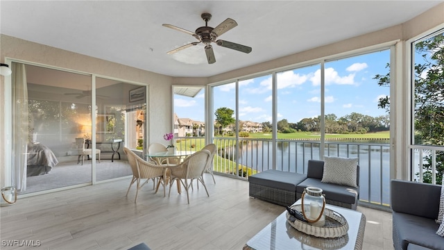 sunroom featuring ceiling fan and a water view