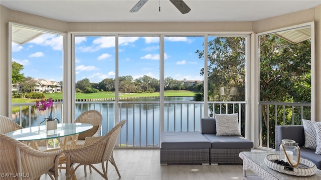 sunroom / solarium with plenty of natural light, ceiling fan, and a water view