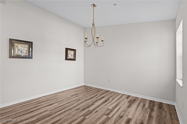 unfurnished room with hardwood / wood-style flooring and an inviting chandelier