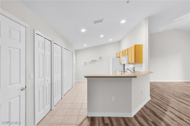 kitchen featuring light brown cabinets, sink, kitchen peninsula, white appliances, and light tile patterned flooring