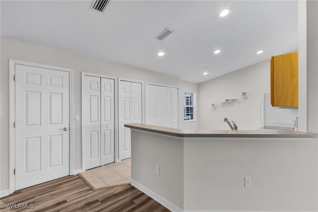 kitchen featuring kitchen peninsula, light hardwood / wood-style flooring, fridge, and sink