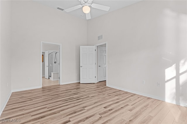 unfurnished bedroom featuring ceiling fan, a high ceiling, and light wood-type flooring