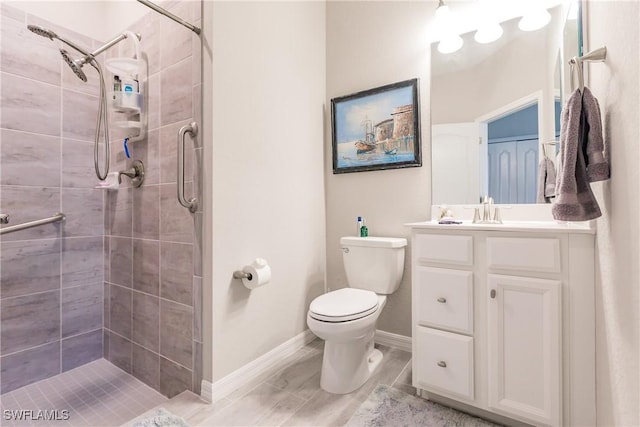 bathroom with a tile shower, vanity, and toilet