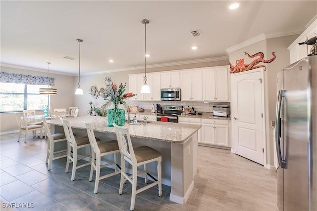 kitchen with a center island with sink, decorative light fixtures, white cabinetry, and stainless steel appliances