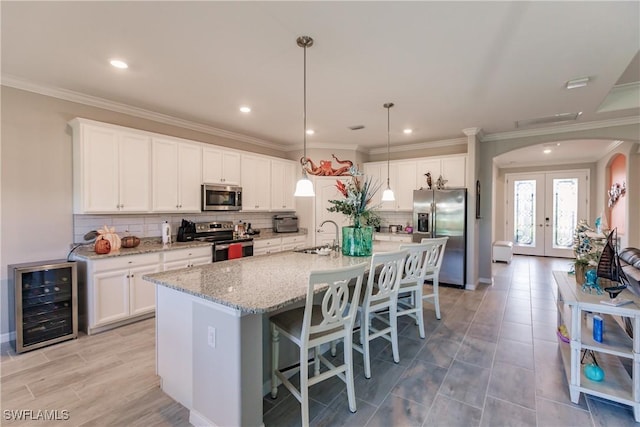 kitchen featuring white cabinets, stainless steel appliances, beverage cooler, and french doors