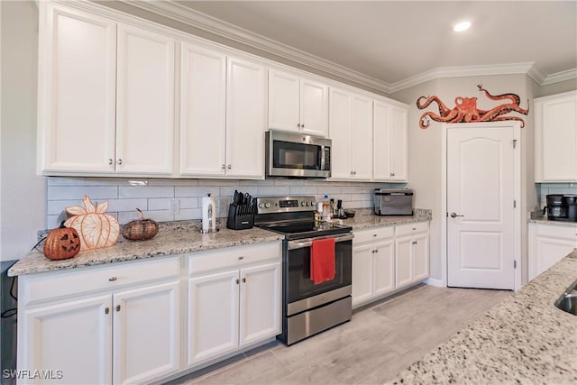 kitchen featuring white cabinets, decorative backsplash, ornamental molding, light stone counters, and stainless steel appliances