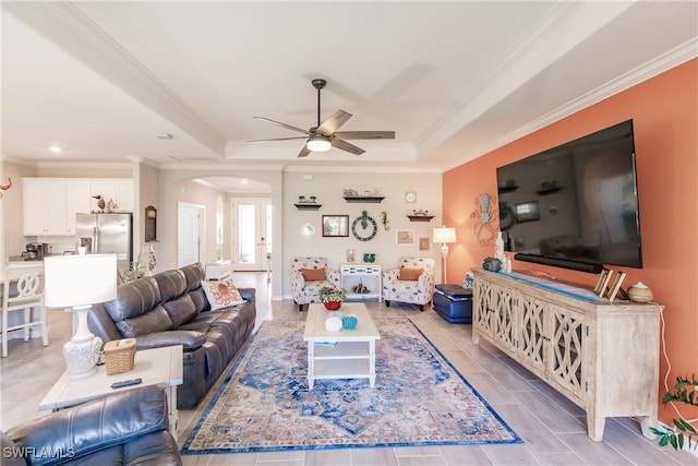 living room featuring a tray ceiling, ceiling fan, and ornamental molding