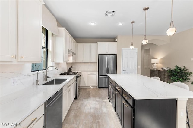 kitchen featuring pendant lighting, a center island, white cabinets, and appliances with stainless steel finishes