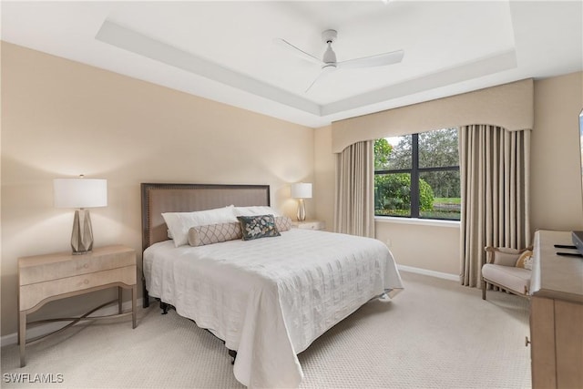 bedroom featuring light colored carpet, ceiling fan, and a tray ceiling