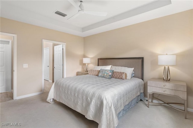 carpeted bedroom with a tray ceiling and ceiling fan