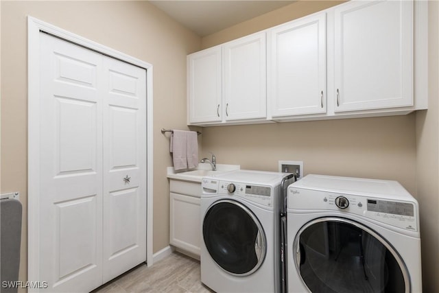 laundry room with independent washer and dryer, cabinets, and sink