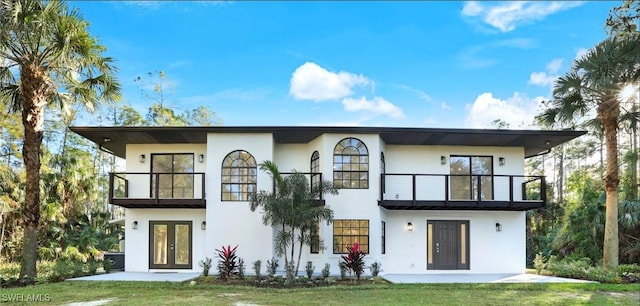 rear view of property with a yard, a balcony, and french doors