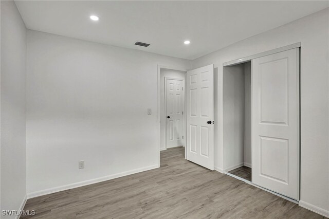 unfurnished bedroom featuring light hardwood / wood-style floors and a closet