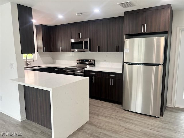 kitchen with stainless steel appliances, sink, light hardwood / wood-style floors, and dark brown cabinetry