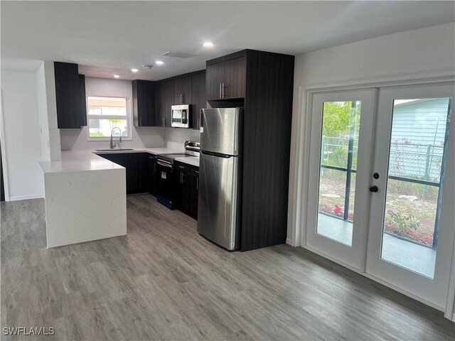 kitchen with sink, french doors, light hardwood / wood-style flooring, and appliances with stainless steel finishes