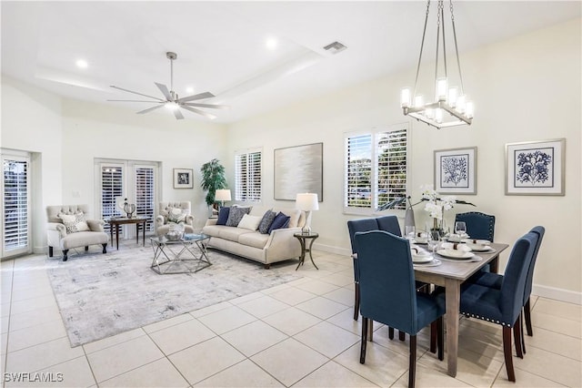 dining space featuring light tile patterned floors, ceiling fan with notable chandelier, a raised ceiling, and french doors