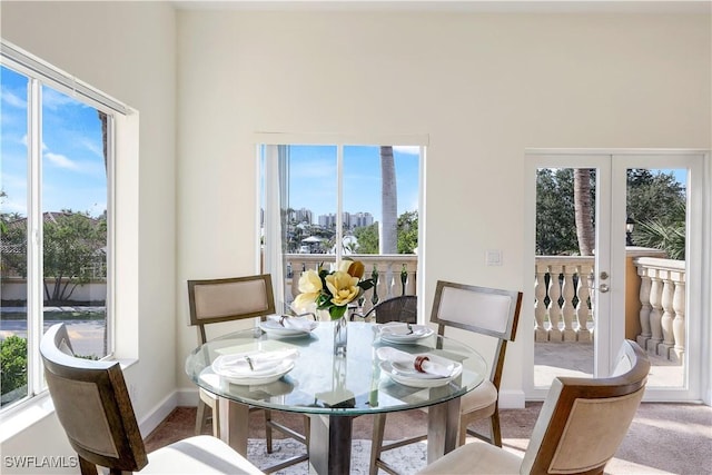 dining room with carpet floors, a healthy amount of sunlight, and french doors