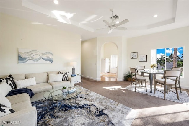 living room featuring ceiling fan, a tray ceiling, and carpet floors