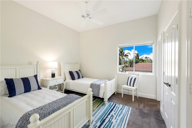 bedroom with ceiling fan, dark carpet, and a closet