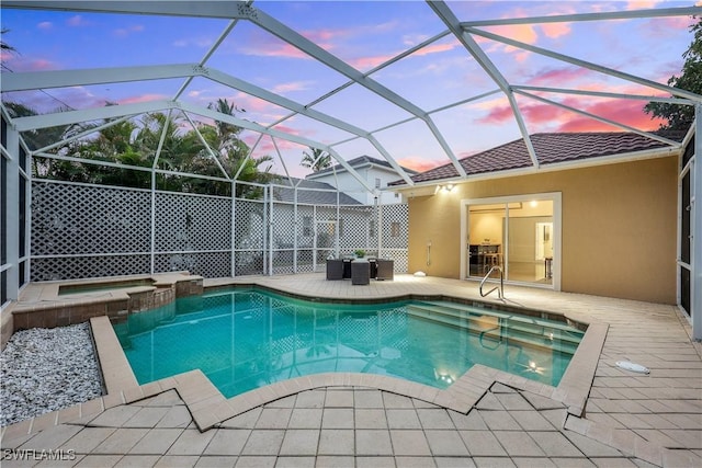 pool at dusk featuring an in ground hot tub, glass enclosure, and a patio area