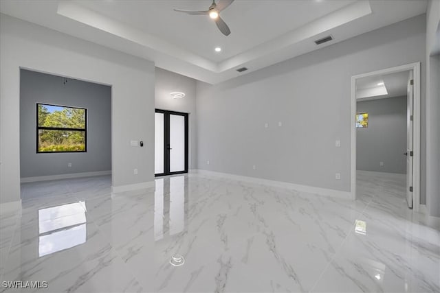 spare room featuring a raised ceiling, ceiling fan, and french doors