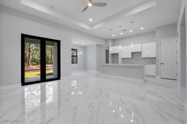 unfurnished living room featuring a tray ceiling, ceiling fan, and sink