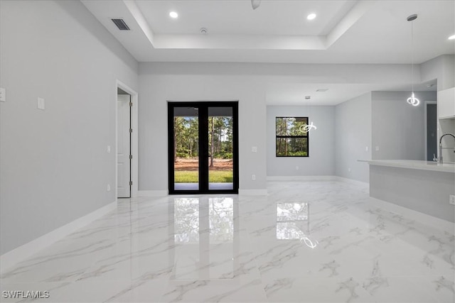 empty room with french doors, a tray ceiling, and sink