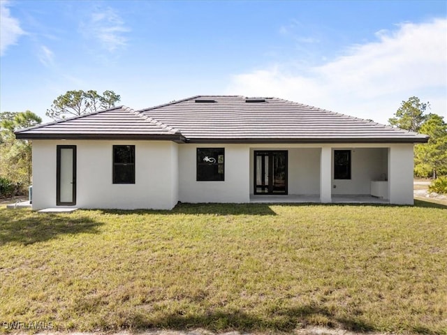 rear view of house featuring a lawn and a patio area