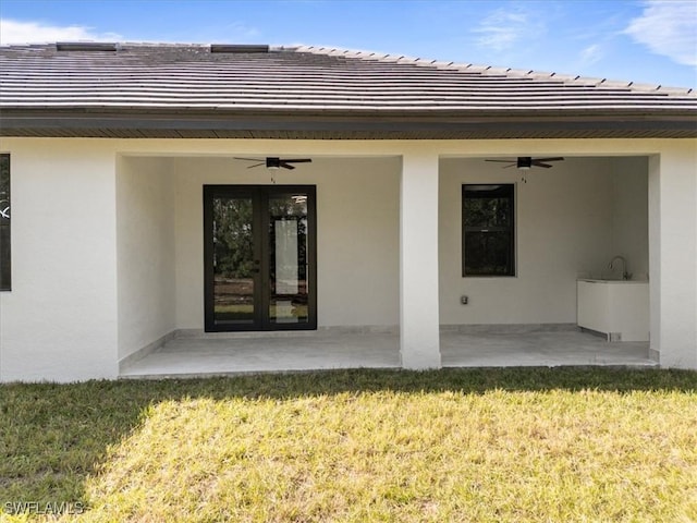 property entrance with a lawn, ceiling fan, and a patio