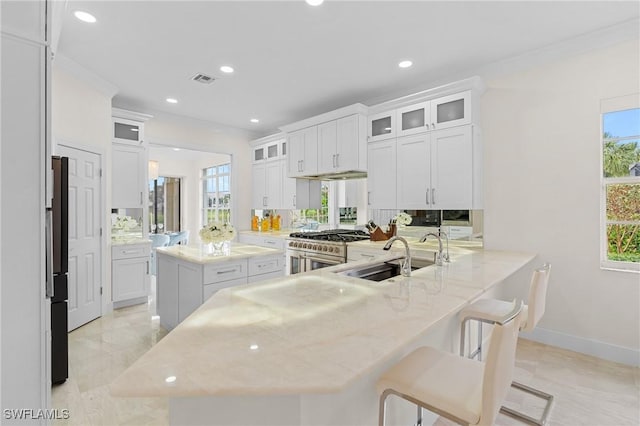 kitchen with sink, white cabinetry, a center island, kitchen peninsula, and range with two ovens