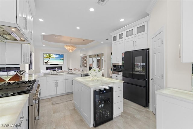 kitchen featuring white cabinets, black fridge, beverage cooler, and a tray ceiling