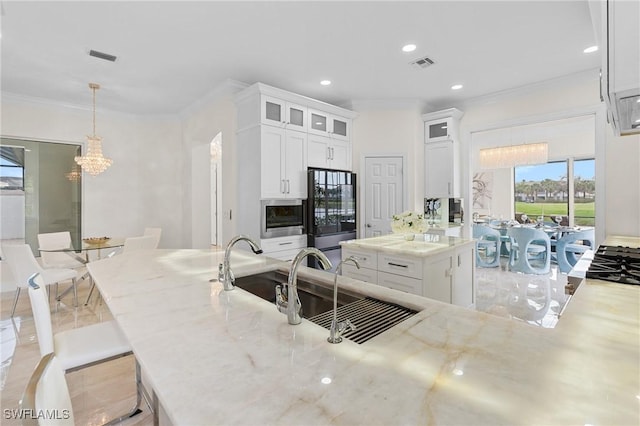 kitchen featuring white cabinetry, fridge, decorative light fixtures, and light stone countertops