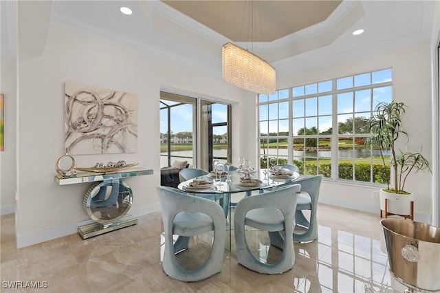 dining room with a raised ceiling, ornamental molding, and a water view