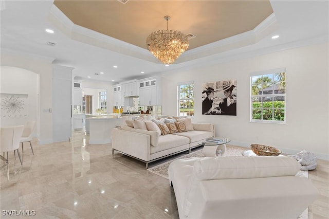 living room with plenty of natural light, a tray ceiling, and a notable chandelier