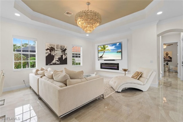 living room with a tray ceiling, ornamental molding, and a chandelier